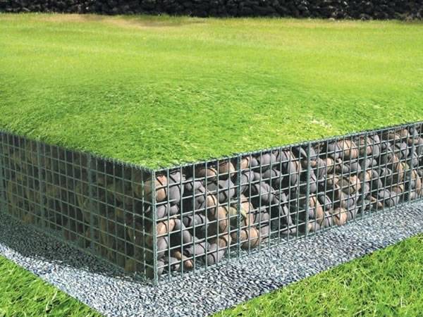 Gabion basket is filled with pebbles with a layer of grass on it.