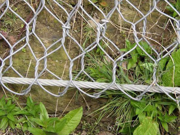 Hexagonal wire rope net covers the hill with boundary rope on a mountain.