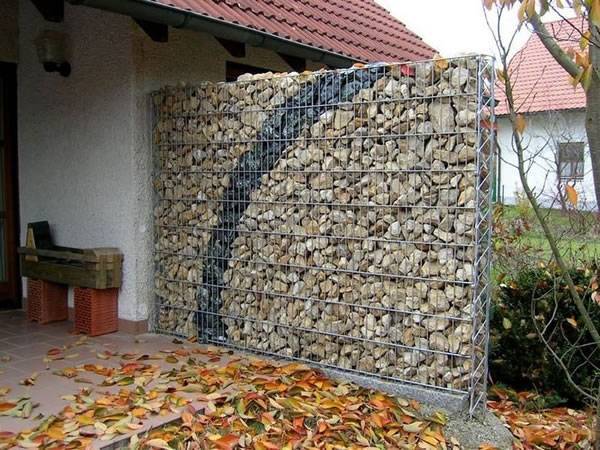 A gabion retaining wall is filled with rocks as retaining wall in a yard.