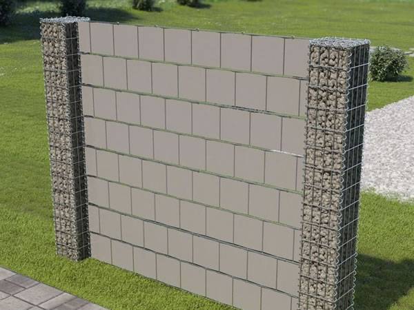 Two gabion posts are connecting the brick wall on the grassland.