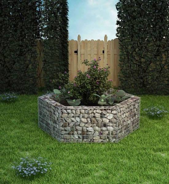 Several flowers and plants are planted in the hexagonal shape gabion planter in the garden.